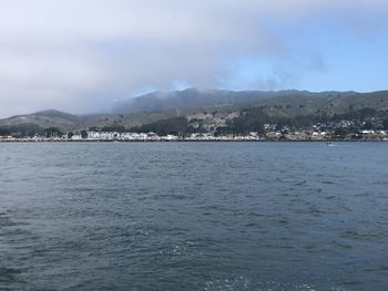 Scenic view of sea by townscape against sky