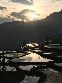 Scenic view of lake and mountains against sky at sunset