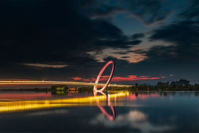 Light trails in amusement park against sky at night