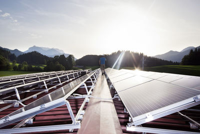 Austria, tyrol, koessen, back view of worker walking on solar plant in the evening