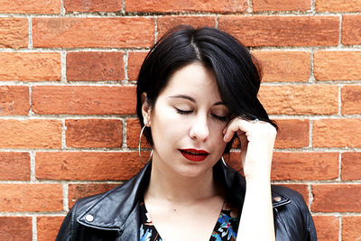 Portrait of woman standing against brick wall