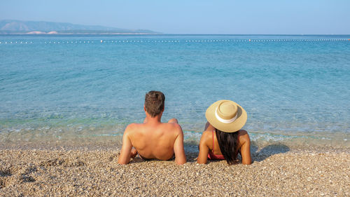 Rear view of woman sitting at beach