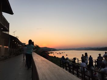 People by lake during sunset