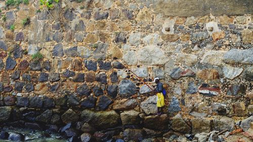 Man fishing while standing against wall