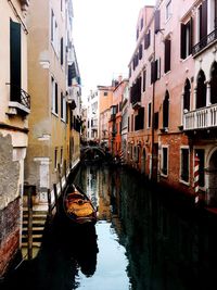 Canal amidst buildings in city against sky