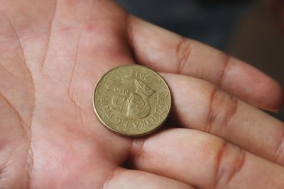 Close-up of hand holding golden coin