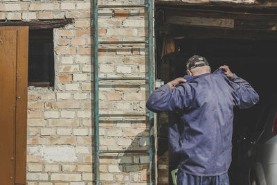 Rear view of man working on old building