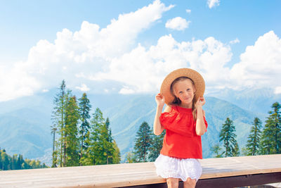 Portrait of young woman standing against sky