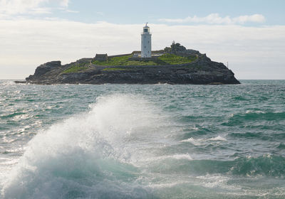 Lighthouse by sea against sky