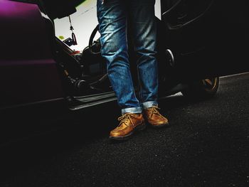 Low section of man standing against motor scooter on road