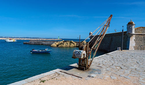 Sailboats moored on sea against clear blue sky