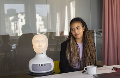 Businesswoman looking at robot voice assistant