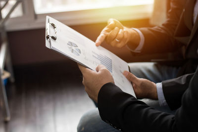 Midsection of man holding paper