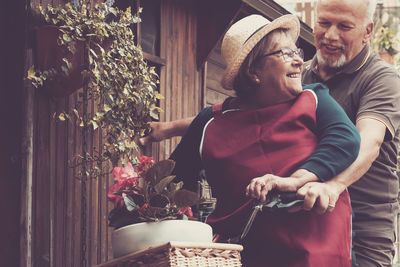 Smiling senior couple sitting on bicycle at yard