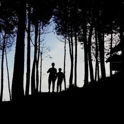 Silhouette of father and son standing in forest