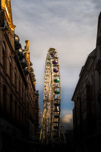 Low angle view of ferris wheel against cloudy sky