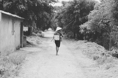 Rear view of fisherman walking on road