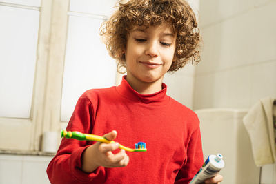 Cute boy looking at toothbrush in home