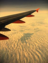 Close-up of airplane wing over landscape against sky
