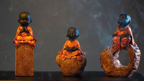 Decorative baby monk sitting on rock and chanting statue. black background, orange cloth wearing