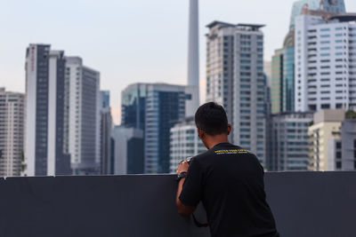 Rear view of man standing against buildings in city