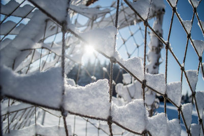 Close-up of snow covered net against sky