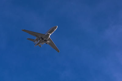 Low angle view of airplane flying against blue sky