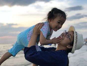 Smiling young woman playing with daughter at beach