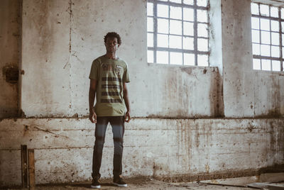 Portrait of man standing against window in abandoned building