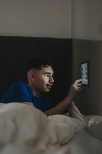 Teenage boy adjusting temperature of bedroom through digital tablet at smart home