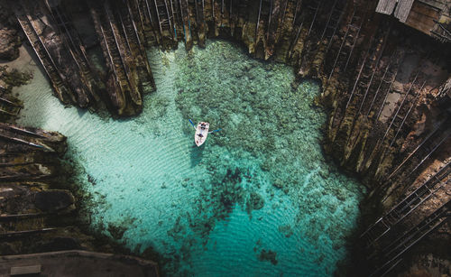 Drone view of white boat on tranquil blue transparent water of sea bay among island formentera