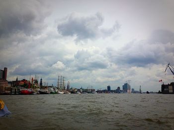 Boats in harbor against cloudy sky