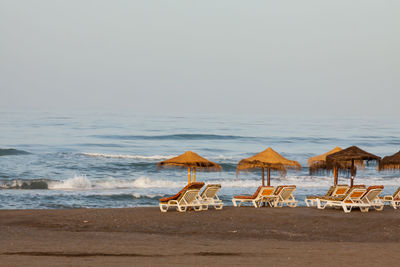 Deck chairs on beach against clear sky