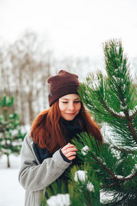 Portrait of smiling young woman against tree during winter