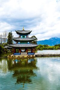 Gazebo in lake against cloudy sky