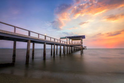 Pier over sea against sky during sunset