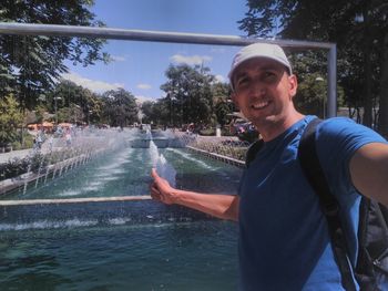 Portrait of man gesturing against fountain at genclik park