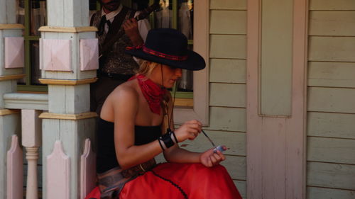 Beautiful woman sitting outside house against musician playing guitar