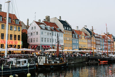 Sailboats in canal amidst buildings against sky