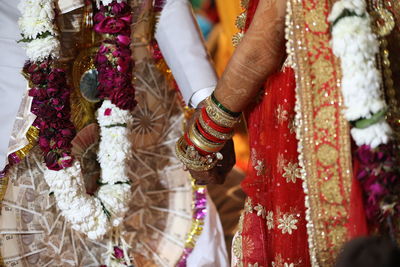 Midsection of bridal couple holding hands during wedding ceremony