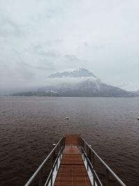 Footbridge over lake against sky