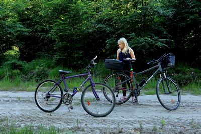 Girl looking away while standing by bicycle on road