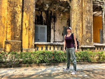 Woman looking away while standing against old abandoned building