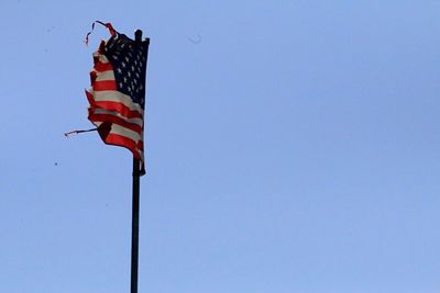 Low angle view of flag against clear blue sky