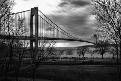 Low angle view of suspension bridge against cloudy sky