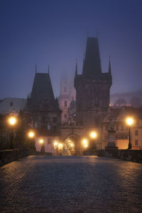 Illuminated charles bridge against buildings at night