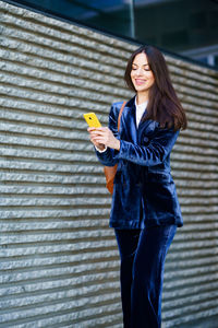 Portrait of young woman standing against wall