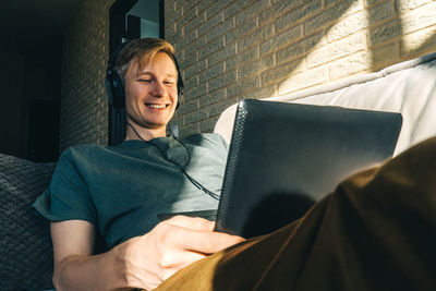 Smiling man using digital tablet while sitting on sofa at home