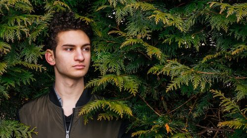 Thoughtful young man standing amidst plants