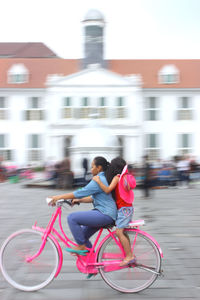 Woman riding bicycle on road in city